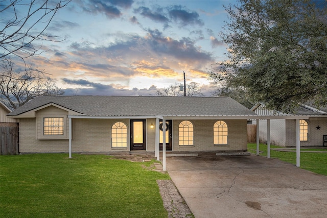 ranch-style home featuring a front lawn, a shingled roof, fence, and brick siding