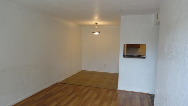 spare room featuring visible vents, baseboards, and wood finished floors