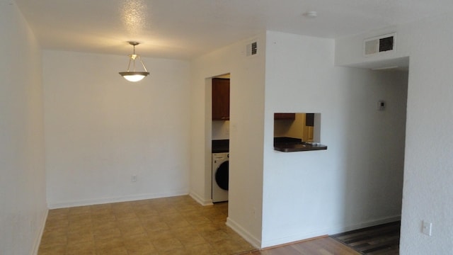 unfurnished room featuring washer / dryer, visible vents, baseboards, and light floors