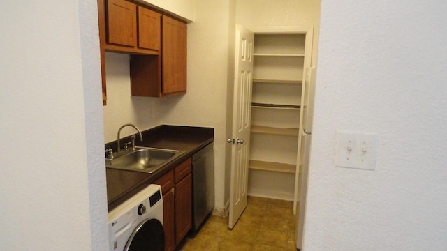 kitchen with a sink, stainless steel dishwasher, brown cabinets, washer / clothes dryer, and dark countertops