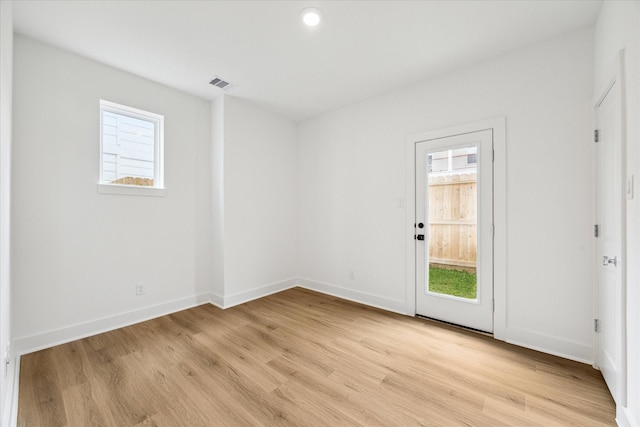 unfurnished room with light wood-style floors, baseboards, visible vents, and a wealth of natural light