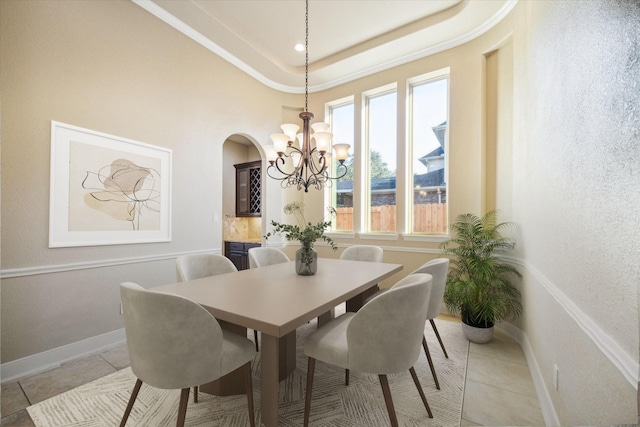 dining room featuring light tile patterned floors, baseboards, arched walkways, a tray ceiling, and a notable chandelier