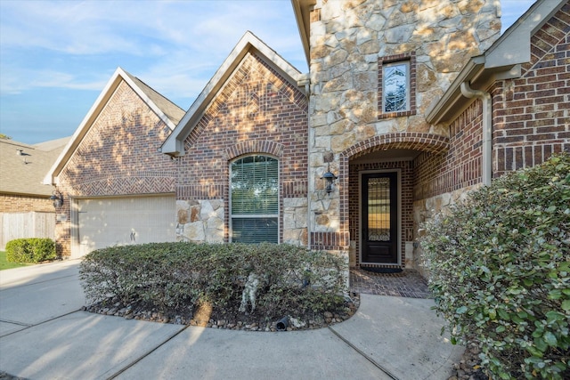 property entrance with concrete driveway, stone siding, brick siding, and an attached garage