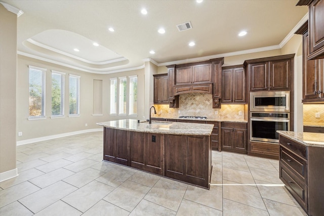 kitchen with visible vents, appliances with stainless steel finishes, a kitchen island with sink, crown molding, and a sink