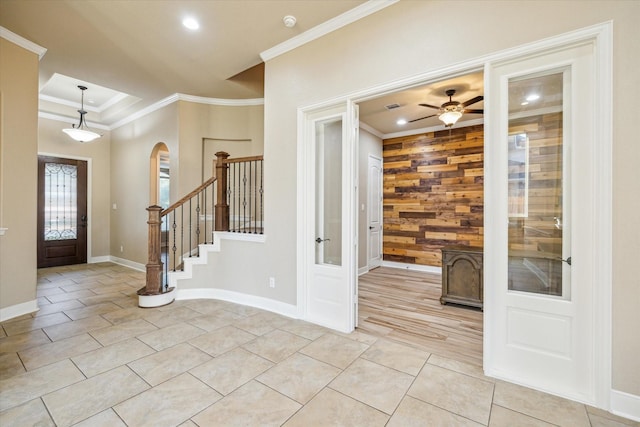 entryway with light tile patterned floors, arched walkways, wooden walls, stairs, and ornamental molding