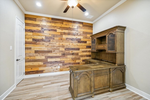 office with light wood-style flooring, ornamental molding, a ceiling fan, wood walls, and baseboards