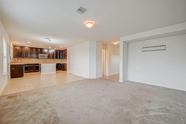 unfurnished living room featuring light colored carpet, visible vents, light tile patterned flooring, a sink, and baseboards