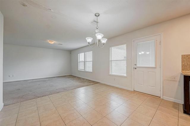 empty room featuring a chandelier, light tile patterned flooring, light carpet, visible vents, and baseboards