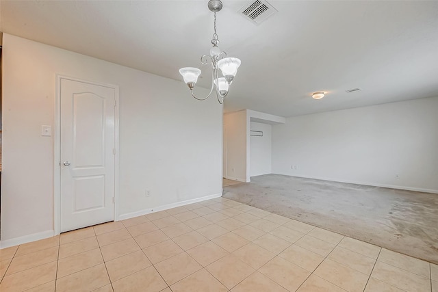 spare room featuring an inviting chandelier, baseboards, visible vents, and light colored carpet