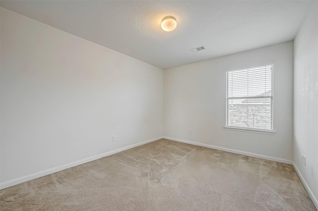 spare room featuring baseboards, visible vents, and light colored carpet