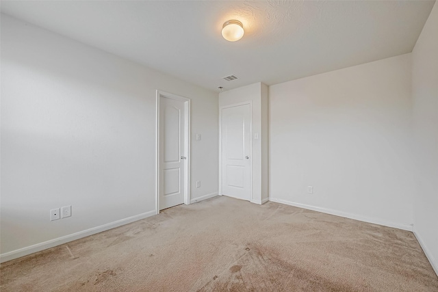 empty room with carpet, visible vents, and baseboards