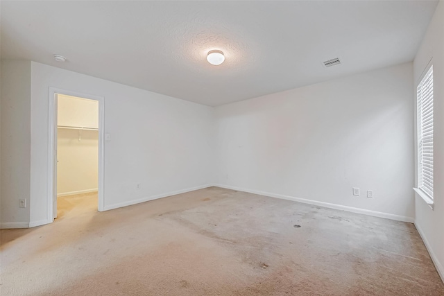 carpeted spare room with visible vents and baseboards