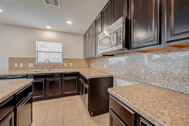 kitchen featuring light countertops, stainless steel microwave, a sink, and visible vents