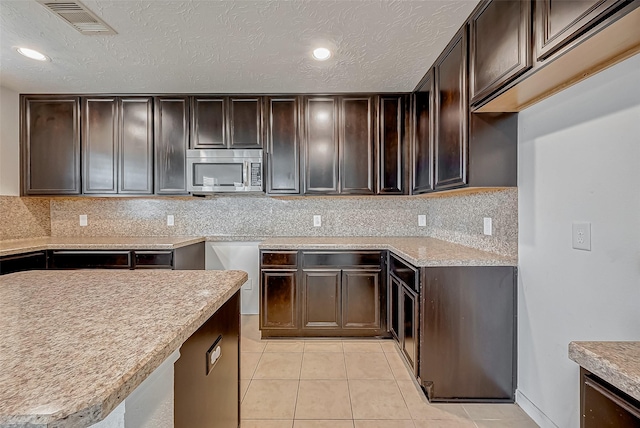 kitchen with stainless steel microwave and dark brown cabinetry