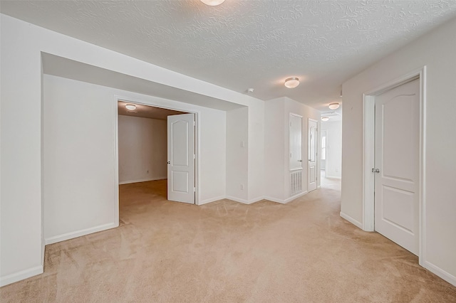 unfurnished room with light carpet, a textured ceiling, and baseboards