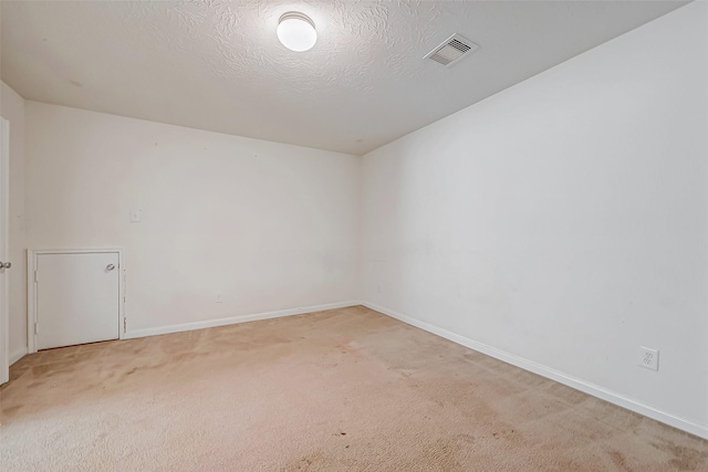 unfurnished room with baseboards, a textured ceiling, visible vents, and light colored carpet