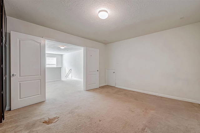 unfurnished room featuring light carpet, baseboards, and a textured ceiling