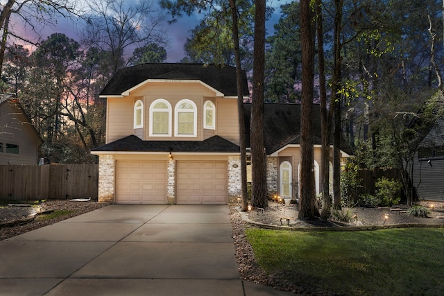 traditional home featuring a garage, stone siding, fence, and concrete driveway