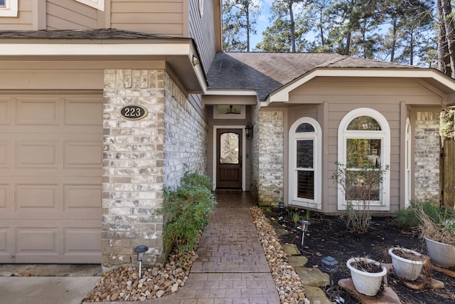 doorway to property with stone siding, a shingled roof, and an attached garage