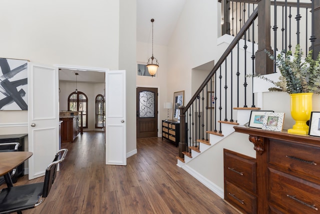 foyer featuring baseboards, stairs, high vaulted ceiling, and dark wood-type flooring