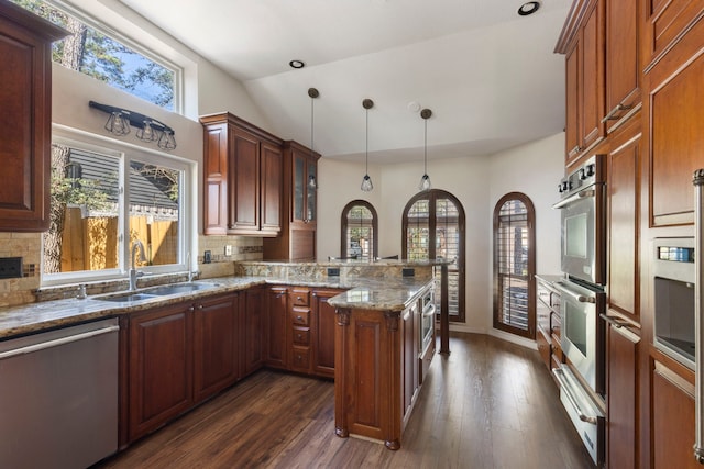 kitchen with stone countertops, decorative backsplash, appliances with stainless steel finishes, a peninsula, and a warming drawer