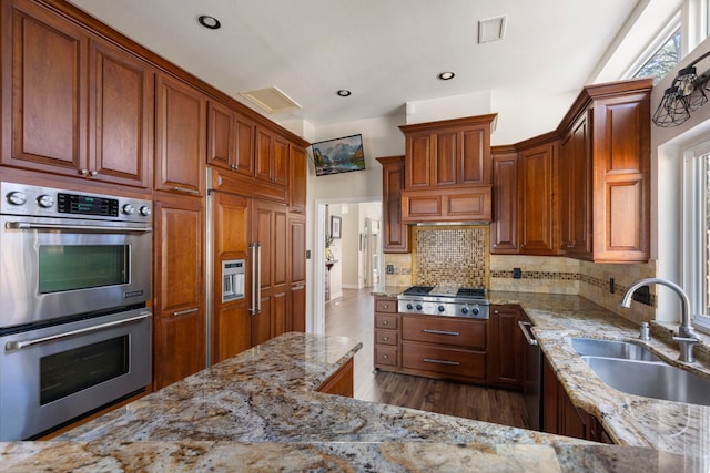 kitchen with light stone counters, a sink, visible vents, appliances with stainless steel finishes, and decorative backsplash