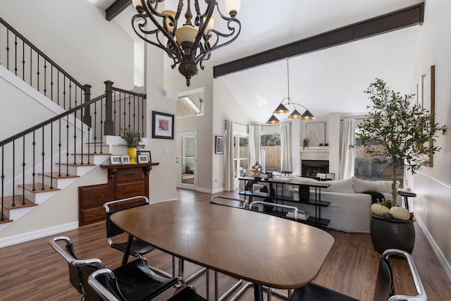 dining room with a chandelier, wood finished floors, a large fireplace, and stairs