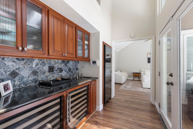 bar featuring dark wood-type flooring, wine cooler, a sink, and decorative backsplash