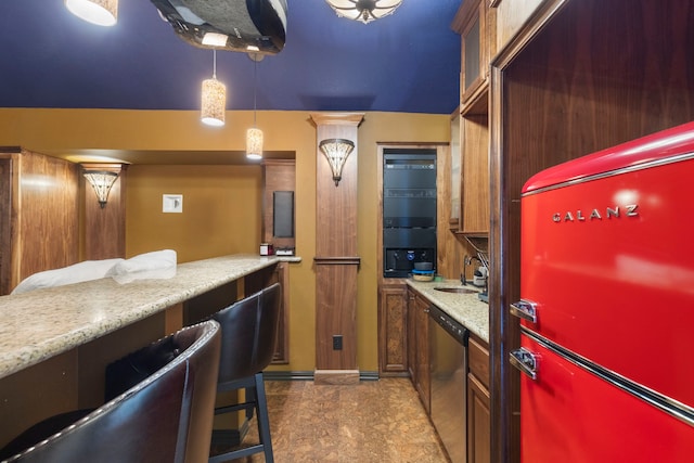 kitchen featuring a sink, hanging light fixtures, stainless steel dishwasher, light stone countertops, and brown cabinetry