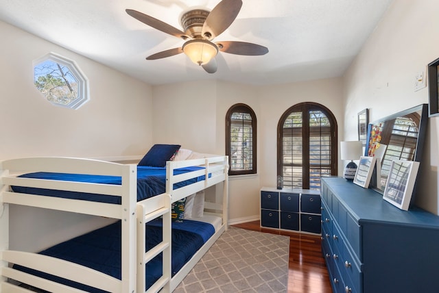 bedroom with dark wood-style floors, ceiling fan, and baseboards