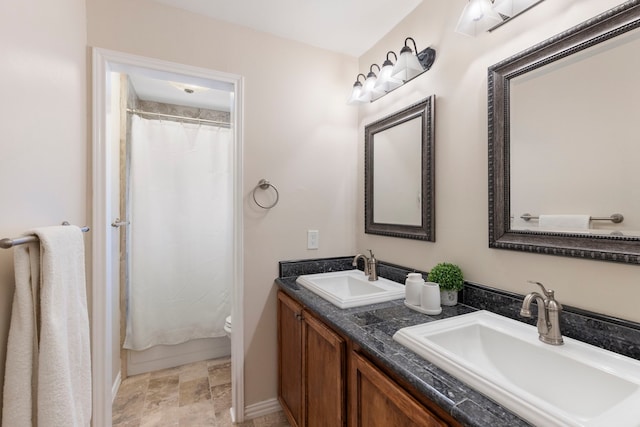 bathroom with toilet, curtained shower, double vanity, and a sink