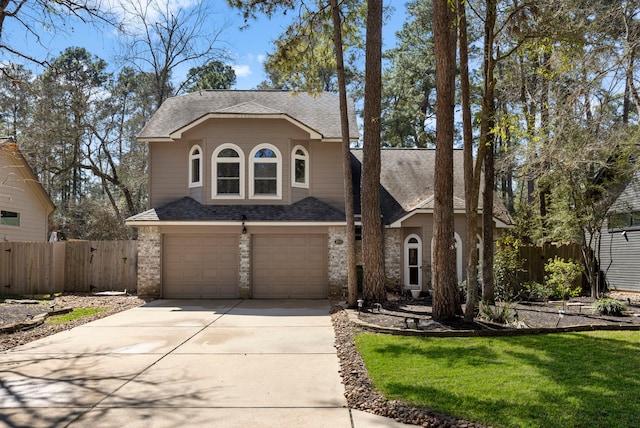 view of front facade featuring driveway, stone siding, an attached garage, and fence