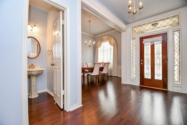 entrance foyer with ornamental molding, wood finished floors, baseboards, and a chandelier