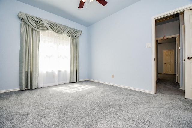 carpeted spare room featuring baseboards, attic access, a ceiling fan, and vaulted ceiling