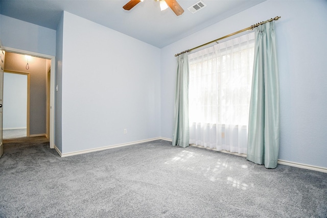 carpeted empty room with vaulted ceiling, baseboards, visible vents, and ceiling fan