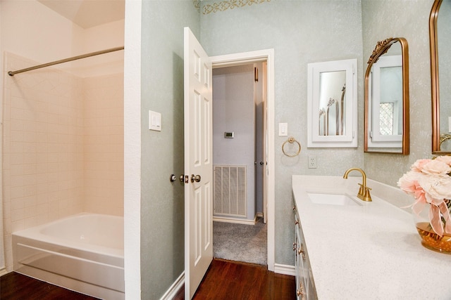 full bathroom with visible vents, baseboards, vanity, wood finished floors, and washtub / shower combination