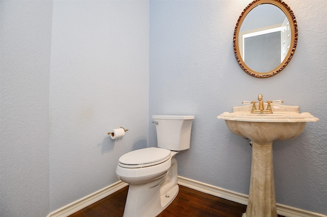 bathroom featuring baseboards, toilet, wood finished floors, and a textured wall