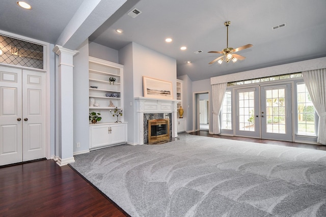 living room featuring built in features, french doors, visible vents, and a high end fireplace