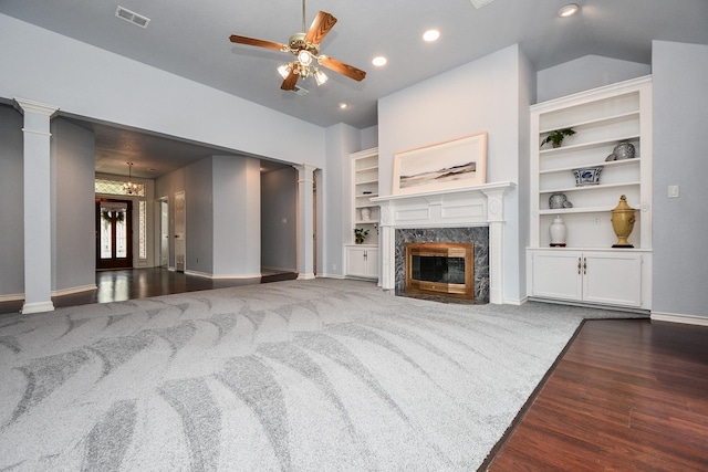 living room featuring visible vents, built in features, a high end fireplace, decorative columns, and ceiling fan