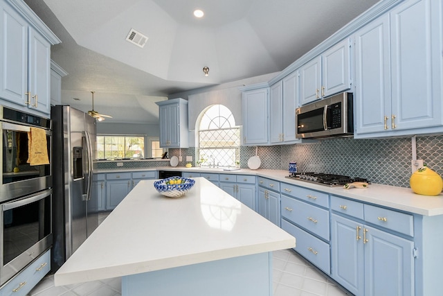 kitchen with visible vents, blue cabinetry, tasteful backsplash, stainless steel appliances, and lofted ceiling