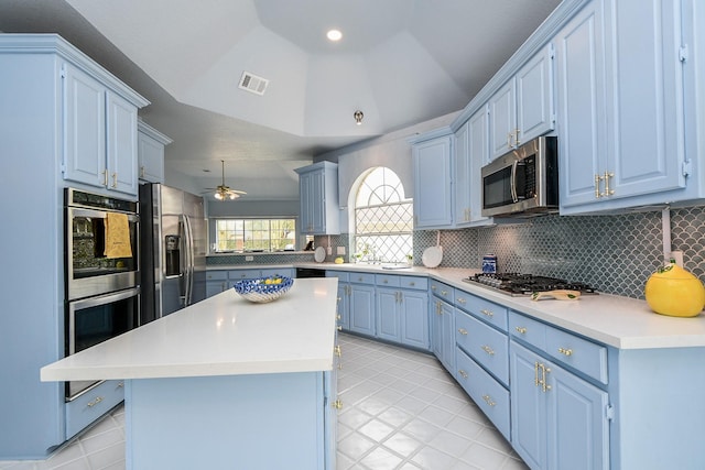 kitchen featuring visible vents, blue cabinetry, appliances with stainless steel finishes, backsplash, and a center island