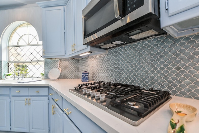 kitchen featuring backsplash, light countertops, blue cabinets, and appliances with stainless steel finishes