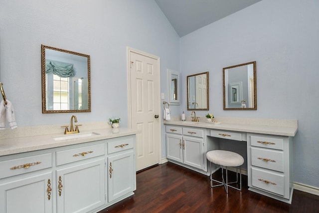 full bath featuring vaulted ceiling, wood finished floors, two vanities, and a sink