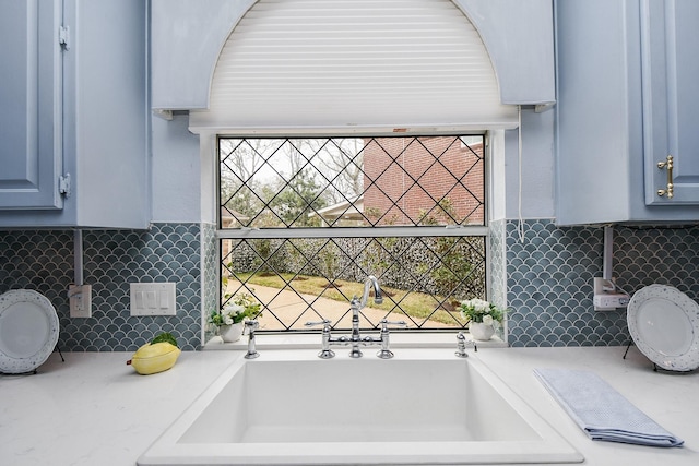 interior space featuring light countertops, blue cabinets, tasteful backsplash, and a sink