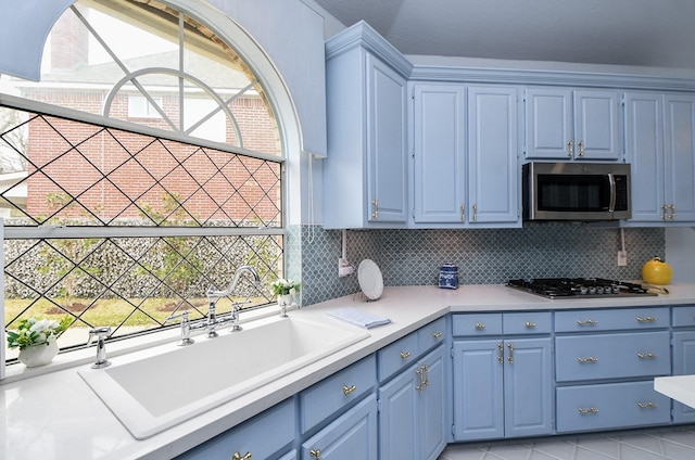 kitchen featuring blue cabinetry, a sink, tasteful backsplash, stainless steel appliances, and light countertops