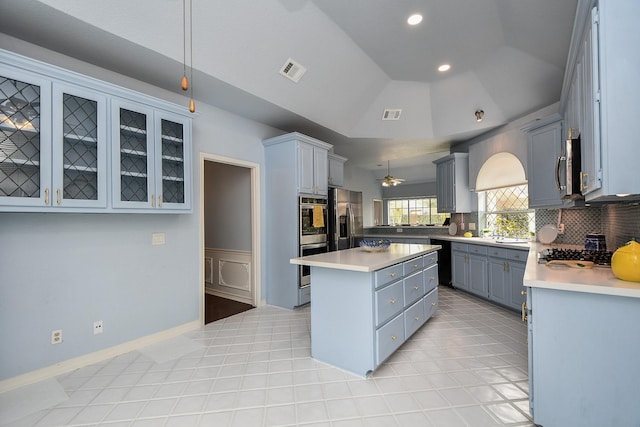 kitchen featuring visible vents, gray cabinetry, a kitchen island, stainless steel appliances, and vaulted ceiling