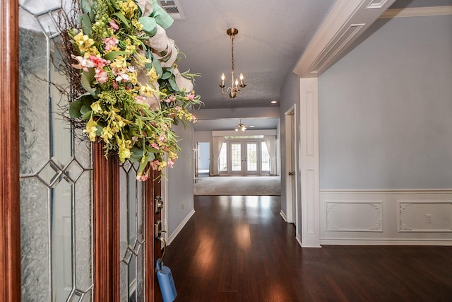 foyer entrance with a wainscoted wall, visible vents, wood finished floors, french doors, and an inviting chandelier