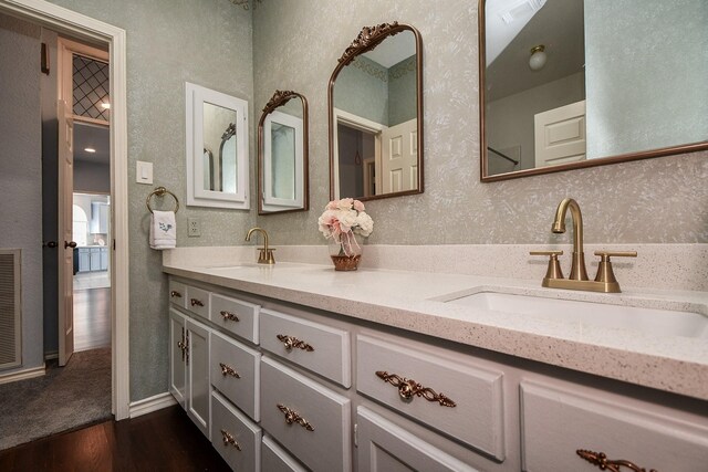 full bathroom featuring a sink, wood finished floors, double vanity, and a textured wall