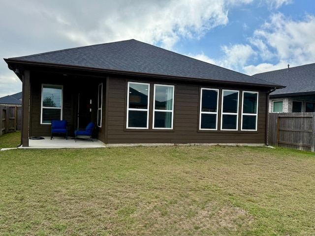 rear view of property with roof with shingles, a fenced backyard, a patio, and a lawn