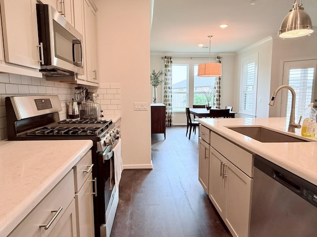 kitchen featuring decorative backsplash, decorative light fixtures, stainless steel appliances, light countertops, and a sink